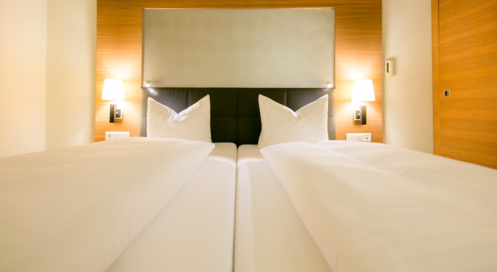 Letto matrimoniale con morbidi cuscini, accenti di legno e luce soffusa nella camera d'albergo